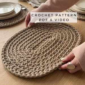 Peut inclure: Un dessous de plat ovale en crochet beige. Le dessous de plat est fait de fil épais et a une surface texturée. L'image montre également une assiette et le texte "CROCHET PATTERN PDF & VIDEO".