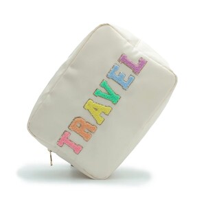 May include: A white travel cosmetic bag with a zipper closure. The word "TRAVEL" is spelled out in colourful, fuzzy letters.