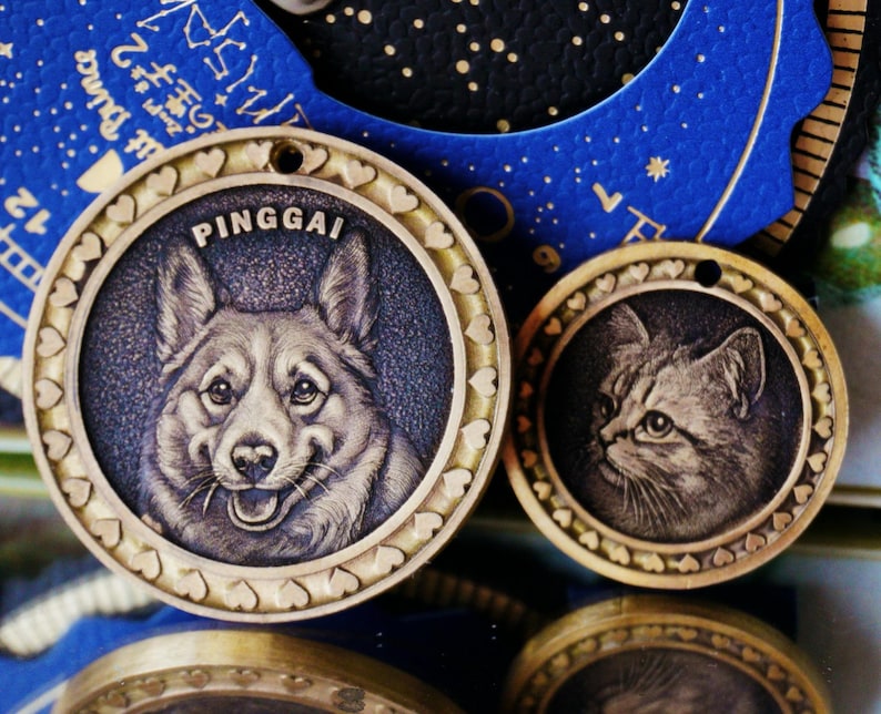 May include: Two brass pet tags. One features a smiling dog with the name "PINGGAI" above it. The other tag has a cat's portrait. Both tags have a heart-shaped border and a hole for attachment.