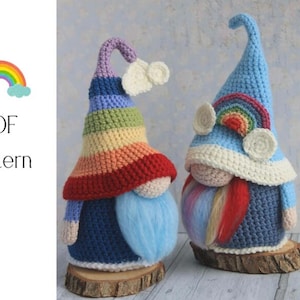 May include: Two handmade crochet gnomes with rainbow-colored hats and beards. One gnome has a rainbow hat and blue beard, the other has a blue hat with a rainbow accent and a rainbow beard. The gnomes sit on wooden bases. Text: PDF Pattern.