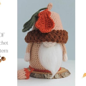 Könnte beinhalten: Eine gehäkelte Zwergenpuppe mit beigem Körper, weißem Bart und braunem Hut mit orangefarbenem Blätterakzent. Die Puppe sitzt auf einer Holzscheibe. Der Text "PDF Crochet Pattern" ist sichtbar.