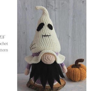 May include: A handmade crochet gnome with a white hat and black eyes, a black beard, and a purple and white collar. A small orange crochet pumpkin sits nearby. The text "PDF Crochet Pattern" is visible.