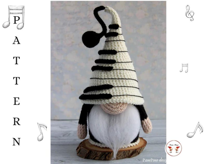 May include: A handmade crochet gnome with a piano key-patterned hat and a long white beard. The gnome's hat is cream-colored with black keys, and it has a black treble clef accent. The gnome is standing on a wooden base.