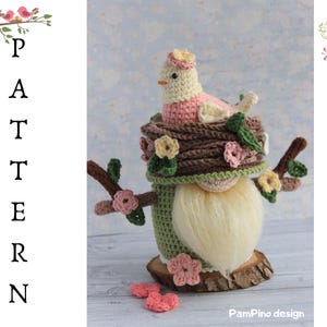 May include: A handmade crochet gnome featuring a bird in a nest. The gnome has a long, cream-coloured beard, a green body, and a brown nest with a pink and cream-coloured bird. The word "PATTERN" is vertically displayed.