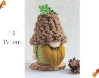 May include: A handmade crochet gnome with a brown textured hat, a long yellow beard, and a green body. The gnome is displayed on a wooden slice and has a small green leaf detail on top. The text "PDF Pattern" is on the left side.