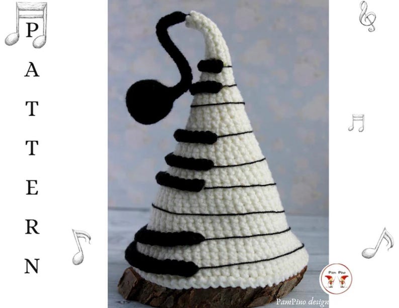 May include: A white crocheted musical tree with black piano keys and a black treble clef. The tree is set on a wooden base. The word "PATTERN" is written vertically on the left side of the image.