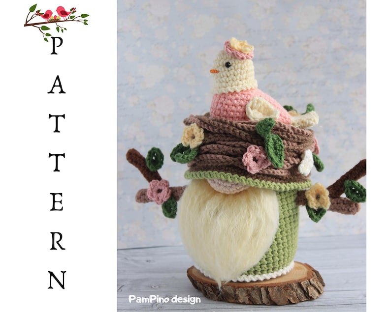 May include: A handcrafted crochet gnome with a bird on a nest. The gnome features a long, fluffy white beard, a green body, and a brown hat decorated with flowers. The bird is pink and cream, with a small yellow beak. The gnome is displayed on a wooden base.