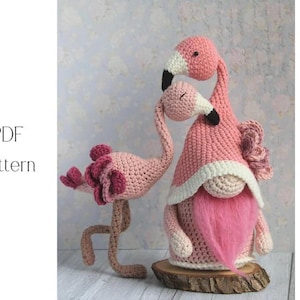 May include: Two handmade crochet flamingo figures. One flamingo stands on two legs, with a long neck and a head with a dark pink beak. The other flamingo is a gnome with a pink beard and a pink hat. The text "PDF Pattern" is on the left.