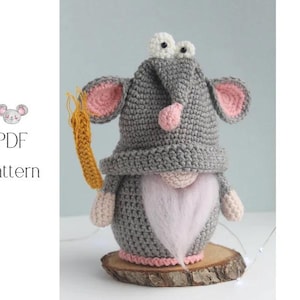 May include: A handmade crochet gnome with a gray hat, pink-lined ears, and a white beard. The gnome holds a yellow carrot and sits on a wooden base. The image also includes the text "PDF Pattern".