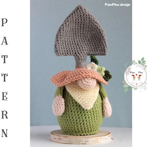 May include: A handmade crochet gnome with a shovel-shaped hat. The gnome has a green body, a peach-colored hat, and a cream-colored beard. The design includes the text "PATTERN" vertically on the left side and "PamPino design" on the top.