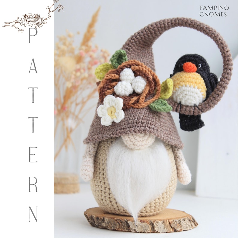 Puede incluir: Una mu&ntilde;eca de gnomo hecha a mano con un gorro puntiagudo marr&oacute;n, una barba blanca y un p&aacute;jaro posado en un marco circular. El sombrero del gnomo est&aacute; adornado con un nido, flores y hojas. La mu&ntilde;eca est&aacute; sobre una base de madera. El texto "PAMPINO GNOMES" es visible.