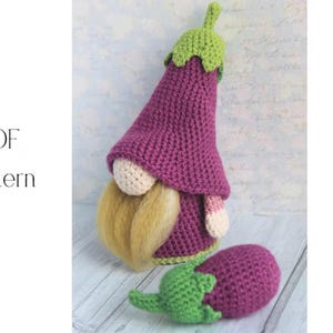 Puede incluir: Un gnomo de ganchillo hecho a mano con forma de berenjena, con cuerpo morado y tallo verde. El gnomo tiene una cara beige, barba rubia larga y un accesorio a juego con forma de berenjena. El texto "PDF Pattern" está en la imagen.