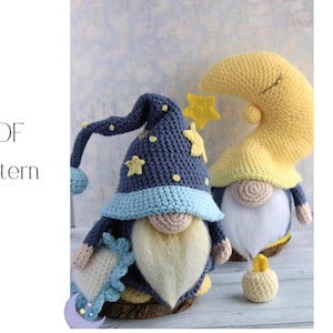 Puede incluir: Dos muñecos de gnomo de ganchillo: uno con un sombrero de mago azul oscuro adornado con estrellas amarillas y un borde azul claro, y otro con un sombrero de media luna amarillo. Una pequeña vela de ganchillo está delante. El texto "PDF Pattern" está a la izquierda.