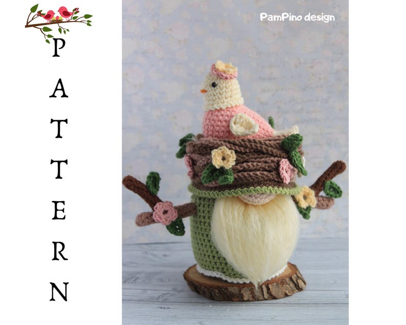 May include: A handmade crochet gnome featuring a bird in a nest design. The gnome has a long white beard, a green body, and a brown nest with a pink bird. The design includes floral accents and is set on a wooden base.