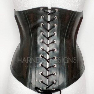 May include: Black latex corset with a lace-up back and the text "HARNESS DESIGNS LEATHER &  ACCESSORIES" printed on the front.