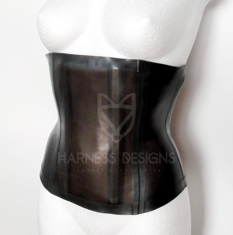 May include: A black latex corset with the text "Harness Designs Leather Accessories" printed on the front.