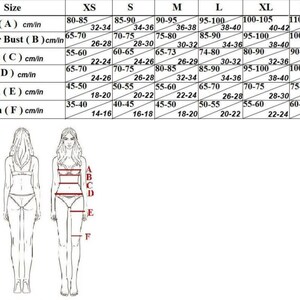 May include: A size chart for clothing with measurements in inches and centimeters. The chart shows the measurements for bust, under bust, waist, hip, thigh, and thigh. The measurements are listed for sizes XS, S, M, L, XL, and XXL.