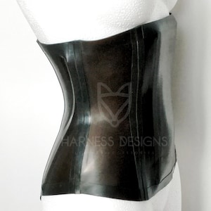 May include: A black latex corset with a smooth, shiny finish. The corset has a front panel with a seam down the center and two seams on each side. The corset is shown on a white mannequin.