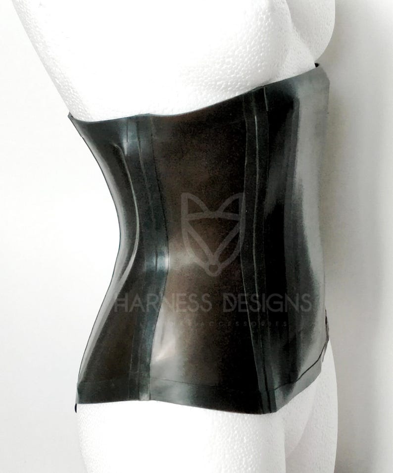May include: A black latex corset with a smooth, shiny finish. The corset has a front panel with a seam down the center and two seams on each side. The corset is shown on a white mannequin.