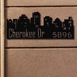 May include: Black metal house number sign with a cityscape silhouette, the text "Cherokee Dr" and the number "5896".