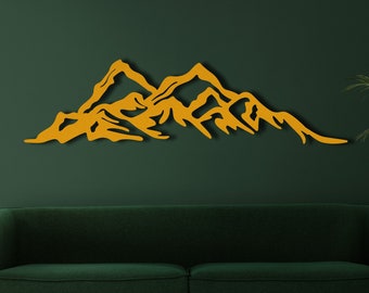 May include: A gold mountain range wall decor silhouette against a dark green wall. The silhouette is made of wood and is a modern home decor accent.