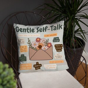 Puede incluir: Una almohada blanca con un dise&ntilde;o floral y el texto "Gentle Self-Talk" en una fuente marr&oacute;n. La almohada presenta una variedad de afirmaciones positivas, como "Soy valioso", "Soy suficiente" y "Cada d&iacute;a es un nuevo comienzo".