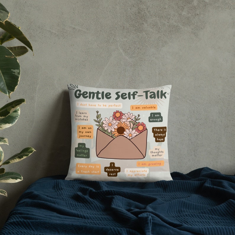 Puede incluir: Almohada blanca con un dise&ntilde;o floral y el texto "Gentle Self-Talk" con afirmaciones positivas como "Soy valioso", "Soy suficiente" y "Mis sentimientos importan".