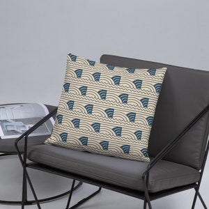 May include: A decorative throw pillow with a cream background and a navy blue geometric pattern of curved lines and shapes.
