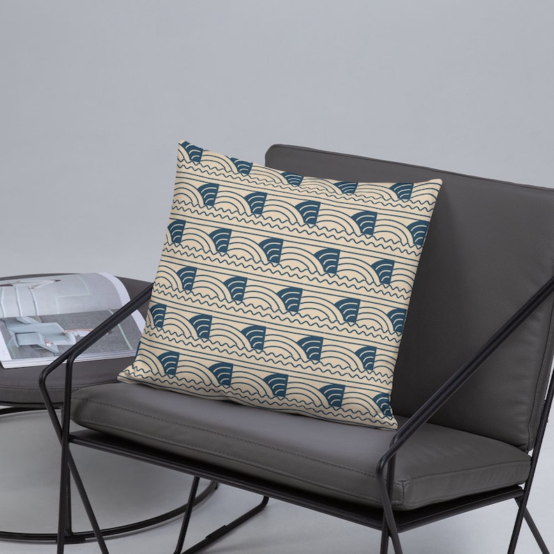 May include: A decorative throw pillow with a cream background and a navy blue geometric pattern of curved lines and shapes.