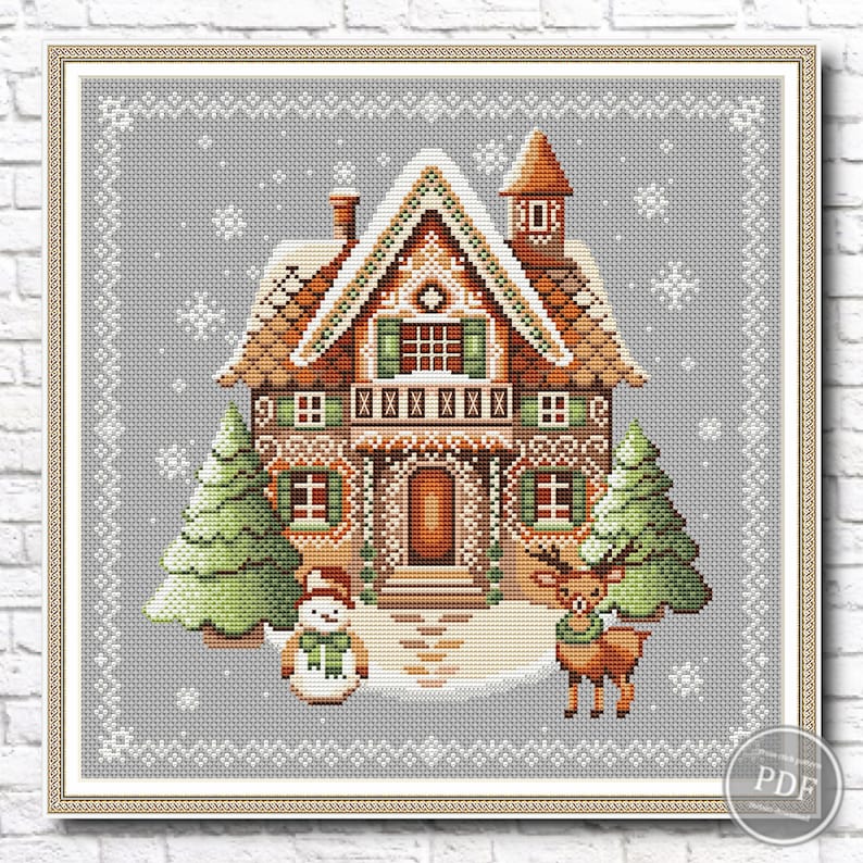 Cross stitch pattern featuring a gingerbread house with brown roof, green shutters, surrounded by two green trees, a snowman, and a reindeer on beige fabric with snowflake pattern.