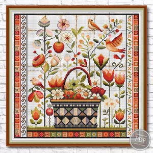 May include: Cross-stitch floral design featuring a basket overflowing with flowers, surrounded by birds and other blooms. The color palette includes red, orange, green, and white, set against a white grid background. The artwork is framed in a brown wooden frame.