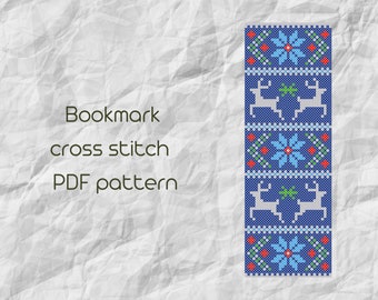 May include: A blue and white cross stitch bookmark pattern featuring a repeating design of reindeer and snowflakes. The pattern is on a white background with the text "Bookmark cross stitch PDF pattern".