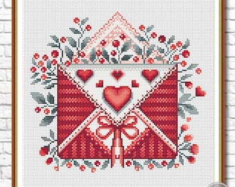 May include: A red and white envelope with a bow and hearts surrounded by green leaves and red berries. The envelope is decorated with a white background and red hearts.