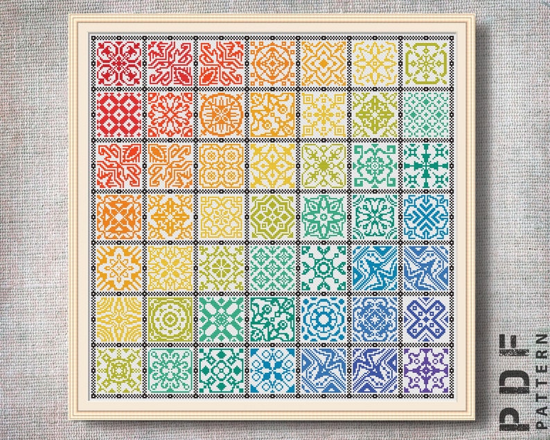 Może przedstawiać: Wz&oacute;r do haftu krzyżykowego przedstawiający tęczę kolorowych geometrycznych płytek. Wz&oacute;r jest oprawiony w białą ramę z czarną ramką.