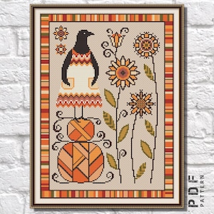 Puede incluir: Patrón de punto de cruz con un pájaro estilizado que lleva un vestido y está de pie sobre una pila de ovillos de lana. El fondo es una tela beige con un borde de rayas naranjas, rojas y amarillas. El patrón incluye girasoles y otros elementos florales.