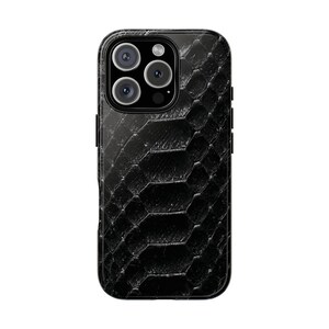 May include: Black phone case with a textured, snake-skin pattern. The case has a rectangular shape with rounded corners and a camera module with three lenses and a flash. The case is designed to fit a smartphone.