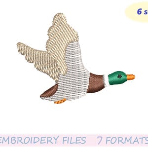 May include: An embroidered design of a flying duck with outstretched wings. The duck features a white and gray body, brown chest, green head, and orange beak. The image includes the text "6 sizes" and "EMBROIDERY FILES 7 FORMATS".