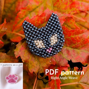 May include: A beaded cat face pin in black, with cream-colored eyes and a pink mouth, sits on a bed of red and orange leaves. The image includes a small paw print pin and text that reads "PDF pattern Right Angle Weave".