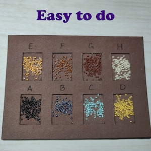 May include: A brown board with eight compartments, each containing a different color of small beads. The compartments are labeled with letters A through H. The text "Easy to do" is written in purple at the top of the board.