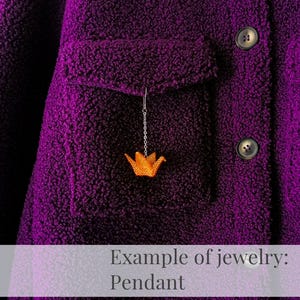 May include: A purple fleece jacket with a small orange origami bird pendant hanging from the pocket.