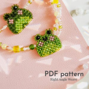 May include: A beaded bracelet with two green frog charms and a beaded chain with white, yellow, and pink beads. The bracelet is on a pink surface. The text "PDF pattern Right Angle Weave" is at the bottom of the image.