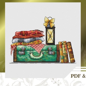 May include: A green vintage suitcase with a brown leather handle, stacked with red, white, and gray blankets. A yellow lantern with a bow sits on top of the suitcase. Four books with brown covers are stacked next to the suitcase.