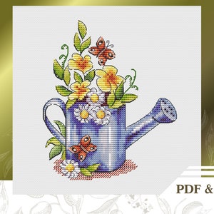 Puede incluir: Una regadera azul con un arreglo floral de flores amarillas y blancas y dos mariposas rojas. Las flores se derraman por la parte superior de la regadera.