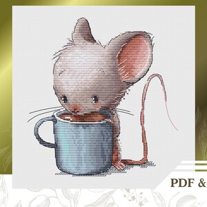Puede incluir: Un patrón de punto de cruz de un lindo ratón gris bebiendo de una taza azul. El ratón tiene la nariz y las orejas rosas. El patrón incluye el texto "PDF & Saga".