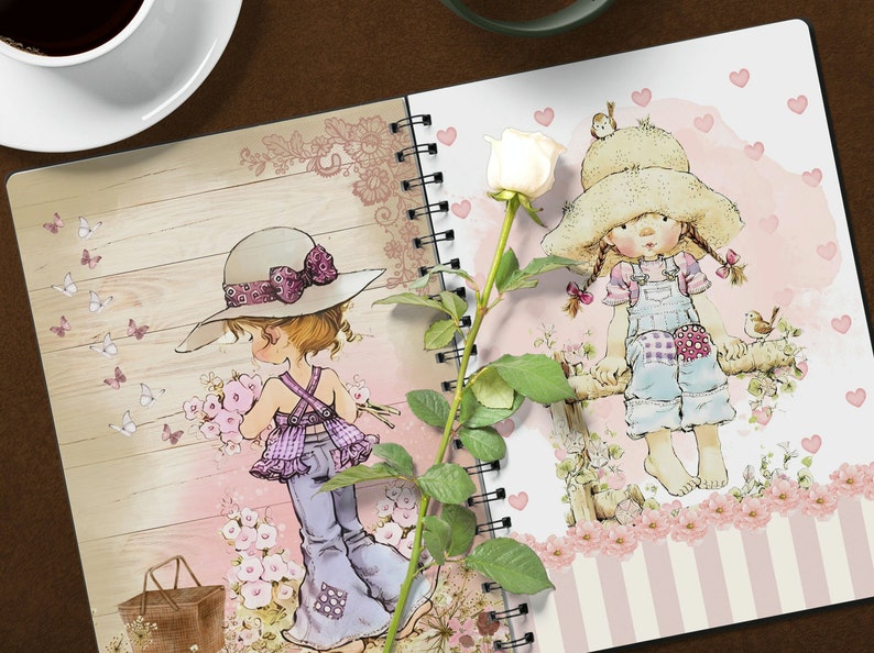 K&ouml;nnte beinhalten: Zwei spiralgebundene Notizb&uuml;cher mit einem rosa-wei&szlig;en Blumendesign. Ein Notizbuch zeigt ein M&auml;dchen mit einem lila Kleid und einem braunen Hut, das Blumen h&auml;lt. Das andere Notizbuch zeigt ein M&auml;dchen mit einem blauen Kleid und einem Strohhut, das auf einem Zaun sitzt. Eine wei&szlig;e Rose mit gr&uuml;nen Bl&auml;ttern liegt zwischen den Notizb&uuml;chern.