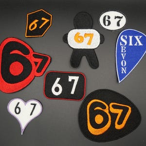 May include: A selection of embroidered patches displaying the number 67 in diverse styles. These include a black and red 67, a white heart-shaped patch with 67, and a blue patch with the words "SIX" and "SEVON".