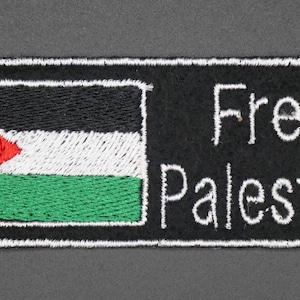 May include: Embroidered patch showing the Palestinian flag with a red triangle, black, white, and green stripes. The text "Free Palestine" is stitched in white on a black background, framed by a white border.