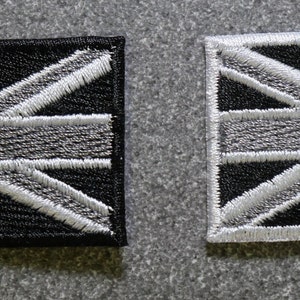 May include: Two embroidered patches featuring the Union Jack flag. The patches are black with white stitching on one and white with black stitching on the other.