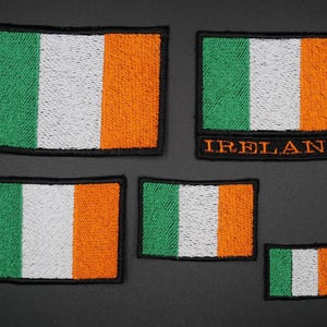May include: A selection of embroidered patches depicting the Irish flag. The patches show the green, white, and orange tricolour design. One patch has the word "IRELAND" in orange lettering.