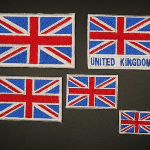 May include: A selection of Union Jack embroidered patches in various sizes. The patches display the flag of the United Kingdom, with a red cross and diagonal stripes on a blue field. One patch includes the text "UNITED KINGDOM" in white lettering.
